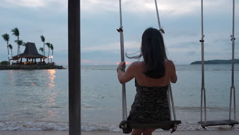 Rückansicht-Einer-Jungen-Frau,-Die-Spaß-Beim-Schaukeln-Auf-Einer-Strandschaukel-Am-Meer-Bei-Sonnenuntergang-Hat,-Shangrila-Resort,-Malaysia