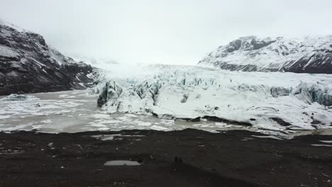 Aufschlussreiche-Drohnenaufnahme-Des-Gletschers-Vatnajökull-In-Island,-Während-Zwei-Personen-Die-Aussicht-Genießen