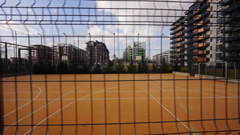 Slow-dolly-left-shot-of-2-basketball-courts-protected-by-a-large-black-fence