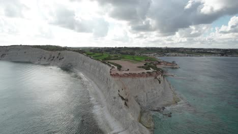 Aerial-View-Over-Ras-il--Fenek-Limestone-Cliff-Side,-With-Tropical-Turquoise-Water-and-Fluffy-White-Clouds,-Malta