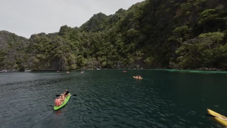 FPV-Drohnenüberflug-Touristen-Beim-Kajakfahren-In-Der-Türkisfarbenen-Wasserbucht-In-Coron,-Philippinen