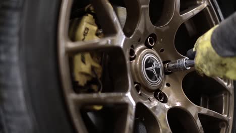 slow-motion-rotating-shot-of-a-mechanic-removing-wheel-nuts-from-a-Mercedes-car