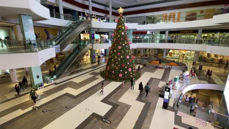 View-Of-Large-Christmas-Tree-Inside-Shopping-Mall-In-Lima,-Peru-With-People-Walking-Past