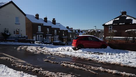 Abandoned-car-crashed-into-wall-during-snow-on-residential-road,-wide-angle