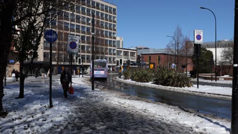 Bus-Fährt-Durch-Verschneite,-Sonnige-Straße-Und-Frau-Geht,-Sheffield