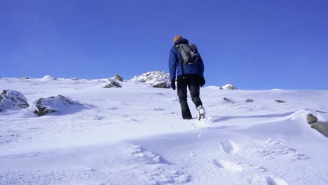 Senderismo-Masculino-En-Un-Día-Ventoso-Sobre-La-Nieve-Hasta-La-Cima-De-Una-Montaña-En-La-Isla-De-Skye-En-Escocia