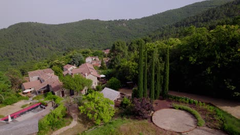 Rustic-villa-in-between-forest-hills-in-the-Branoux-les-Taillades-French-countryside,-Aerial-dolly-left-approach-shot