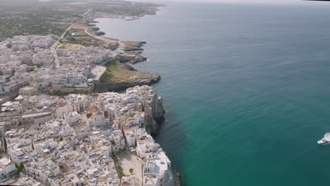 Wide-aerial-side-to-side-shot-showing-the-town-of-Polignano-a-Mare-and-the-cliffs-and-sea-that-it-sits-next-to-in-Italy