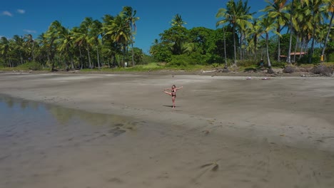 Woman-practicing-yoga-on-beach-on-tropical-island