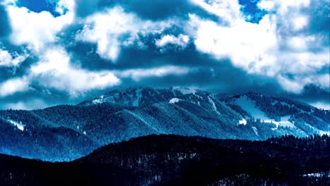 Lapso-De-Tiempo-De-Montaña-De-Invierno,-Nubes-Blancas-Gruesas-Azules-Dramáticas-Girando,-Estación-De-Esquí-De-Poiana-Brasov-En-El-Fondo,-Brasov,-Rumania