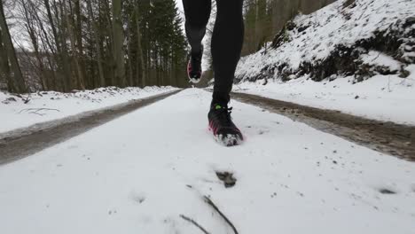 Close-up-front-view-of-a-trail-runner-on-wintery-forest-trails-on-snow