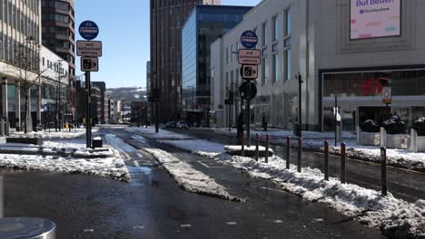 4x4-drives-through-city-centre-street-on-snowy,-sunny-day-as-people-cross-road