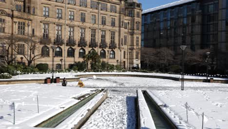 Peace-gardens-and-town-hall-covered-in-snow-on-sunny-day,-Sheffield,-panning