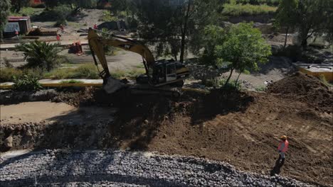 Excavator-dredging-soil-in-city-park-construction-site-working,-Mexico