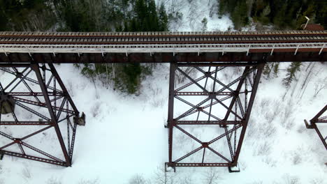 Drohnenflug-über-Eine-Eisenbahnbrücke-Im-Winter-Mit-Schnee-Auf-Dem-Boden