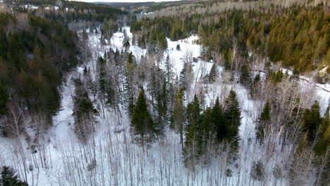 Drone-flight-over-a-small-cabin-close-to-a-frozen-river-in-winter-in-Percé,-Québec,-Canada