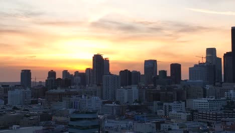 Amazing-sky-rising-over-buildings-in-downtown-Los-Angeles-at-sunset,-establishing-city-aerial-view