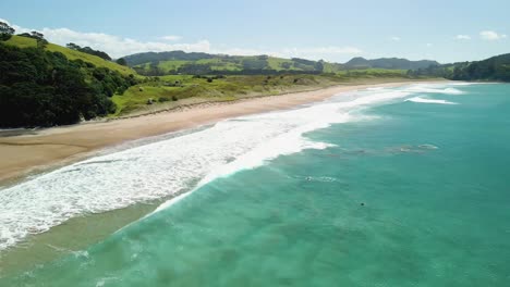 Cinematic-drone-view-over-surf-beach-in-New-Zealand's-North-Island