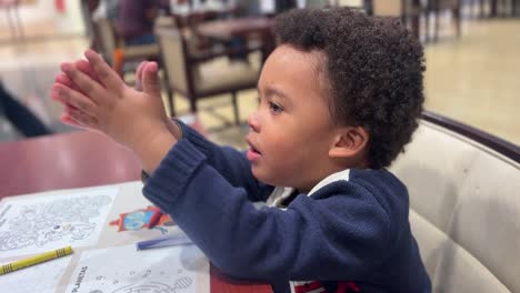 Divertido-Niño-Negro-Exótico-De-3-Años-Jugando-Con-Crayones-Sentado-Dentro-De-Una-Cafetería