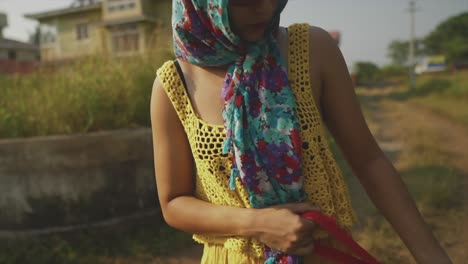 Young-girl-or-brunette-woman-dressed-in-yellow-with-a-headscarf-and-sunglasses-walking-a-dog-in-slow-motion