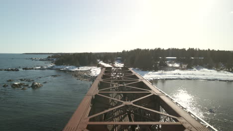 drone-flying-over-a-train-bridge-over-the-ocean-in-Chandler,-Québec,-Canada