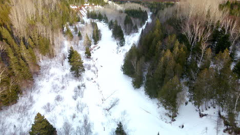 Drone-flight-over-a-frozen-river-in-winter-in-Percé,-Québec,-Canada