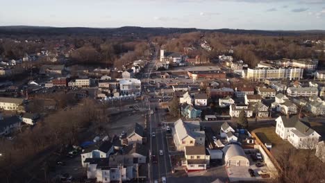 Drone-descending-over-commuter-traffic-on-central-street-in-the-town-of-Hudson,-Massachusetts-during-winter