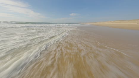 Aerial-fpv-racing-drone-flying-over-sea-waters-along-beach,-Soustons,-Landes-department-in-France