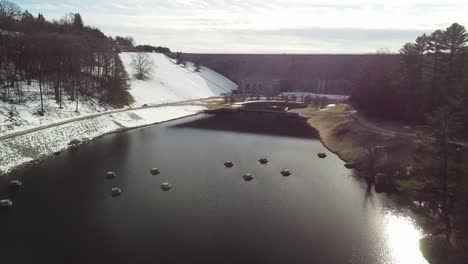 Drone-approaching-the-Wachusett-Reservoir-Dam-from-the-low-side,-looking-at-the-decorative-fountain-at-the-base-of-the-dam