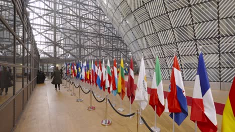 Person-walking-along-EU-member-state-country-flags-in-the-European-Council-building---Brussels,-Belgium