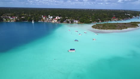 Luftaufnahme-Von-Booten-In-Der-Lagune-7-Farben-Mit-Grünen-Tropischen-Wäldern-Und-Den-Wohngebieten-Im-Hintergrund