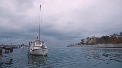 Boat-flying-a-Turkish-flag-docked-in-a-canal-on-a-cloudy-day,-master-view
