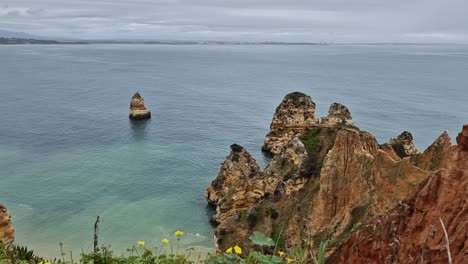 Praia-Dona-Ana,-8600-500-Lagos,-Portugal-in-March-on-a-cloudy,-rainy-day-facing-the-sea-with-rock-formations,-and-the-beach-in-the-shot