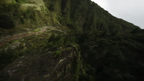 Fast-FPV-aerial-passes-woman-by-stream-by-forested-Azores-mountains