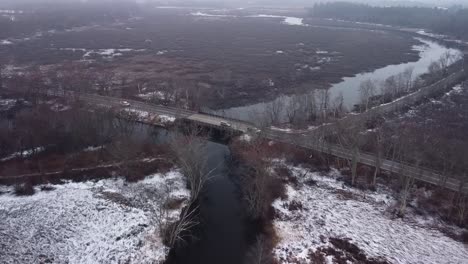 Drone-flying-towards-a-bridge-over-the-Assabet-river-in-King-Phillip's-woods-wetlands-in-Sudbury,-Massachusetts