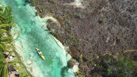 Aerial-view-above-people-paddling-in-the-Laguna-Bacalar,-in-sunny-Mexico---birds'-eye,-drone-shot