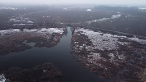 Drone-flying-through-fog-near-a-bridge-near-wetlands-in-Sudbury,-Massachusetts