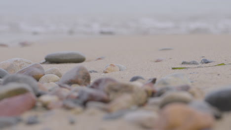 Low-Angle-Shot-Over-Pebbles-On-Redlowo-Beach-In-Gdynia-With-Waves-Breaking-In-Background