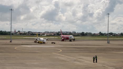 Aviones-De-Pasajeros-Estacionados-En-La-Pista-De-Un-Aeropuerto-Con-Personal-De-Tierra-En-Primer-Plano-En-Cebu,-Filipinas