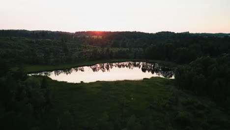 Aerial-ascent-of-calm-lake-at-sunset,-Hällingsjö,-Sweden