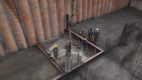 Aerial-view-of-construction-workers-laying-wet-cement-using-automatic-pump