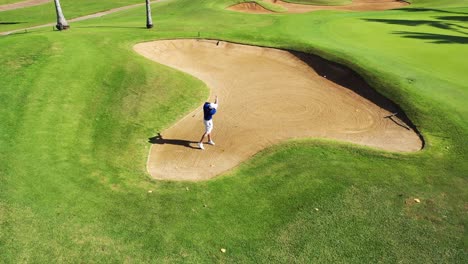 Golfer-lofting-ball-out-of-bunker-Aerial-shot-4K