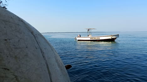 A-small-speed-boat-moored-in-the-calm-blue-waters-with-a-view-of-half-a-large-white-buoy-in-the-foreground
