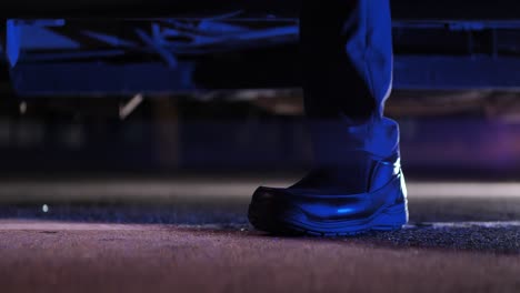 Man-gets-out-of-car-on-parking-lot-at-night,-shoe-close-up