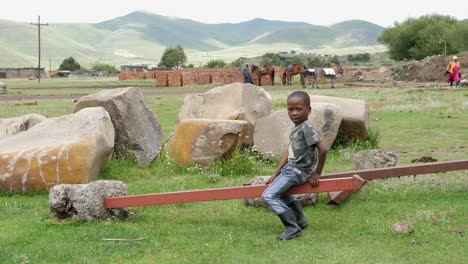 Ein-Junger-Afrikanischer-Junge-In-Lesotho-Findet-Einen-Weg,-Alleine-Eine-Wippe-Zu-Fahren