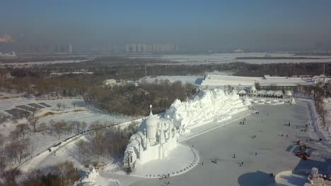 Aerial-spirals-slowly-over-ice-sculptures-in-winter-city,-Harbin-China