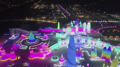 Night-aerial-flyover:-Colorful-frozen-ice-fest-grounds,-Harbin-China