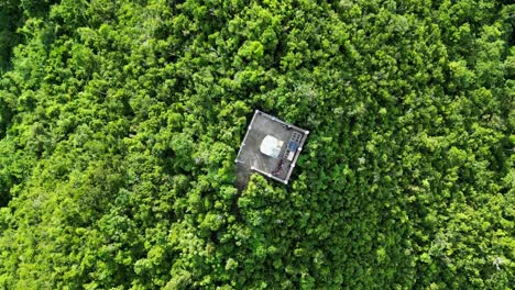 Aerial-Top-Down-Orbit-View-of-white-lighthouse-atop-a-lush-jungle-covered-hill-in-the-island-of-Catanduanes,-Philippines