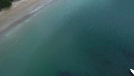 Drone-shot-of-the-ocean,-slow-tilt-up-to-reveal-beach-and-jungle-of-Mexico