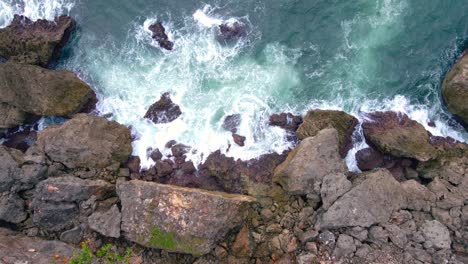 Overhead-drone-shot-of-big-sea-wave-hits-the-rocks-on-the-beach